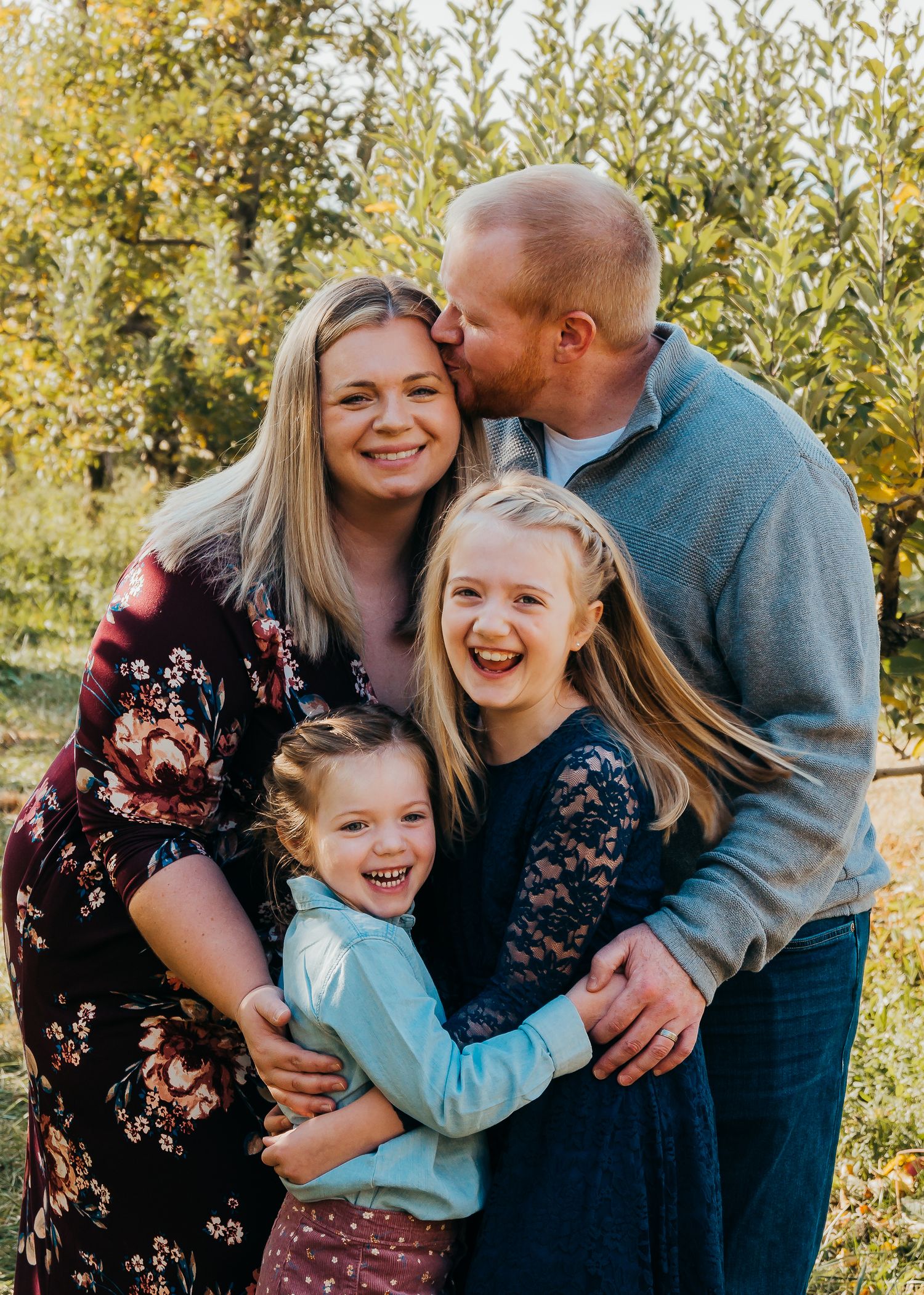 Daughters laughing as dad kisses mom on the head