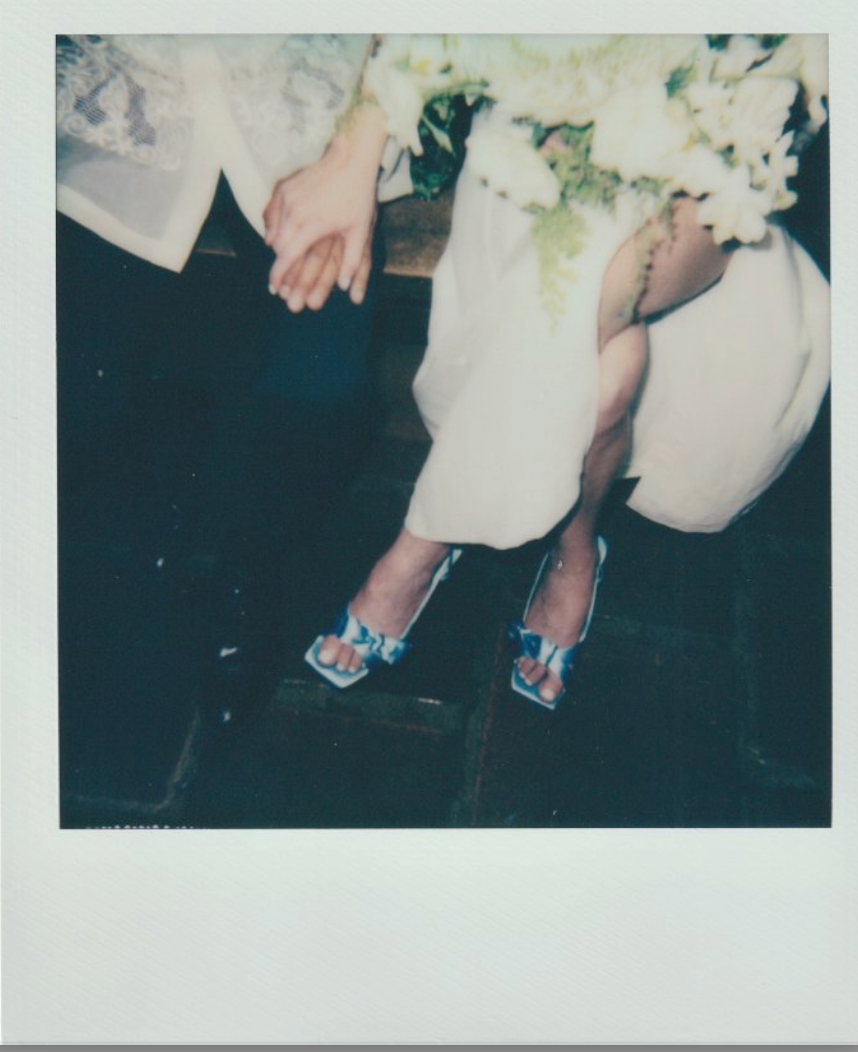 Vintage polaroid detail shot of bride's blue shoes against dark floor.