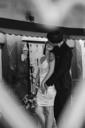 A black and white photo shows a romantic couple eloping at the Little White Chapel, with a bouquet visible.