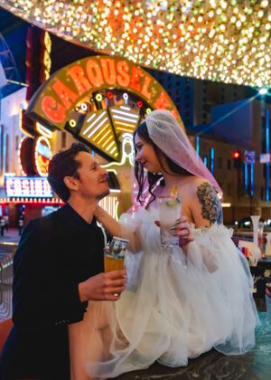 A couple celebrates their wedding moment outside an illuminated casino in Las Vegas with glittering lights overhead.