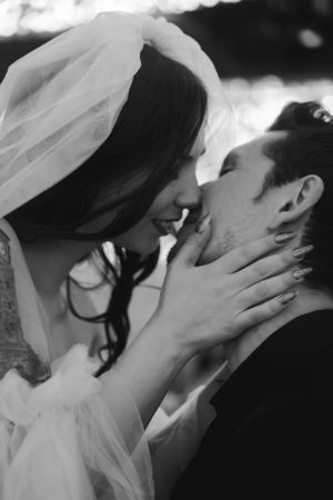 A tender black and white wedding photo captures an intimate moment between newlyweds sharing a romantic kiss.