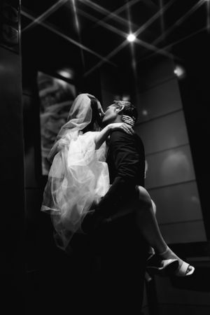 A dynamic black and white photograph captures a couple's passionate kiss in an elevator after Las Vegas elopement at Sure Thing Chapel.