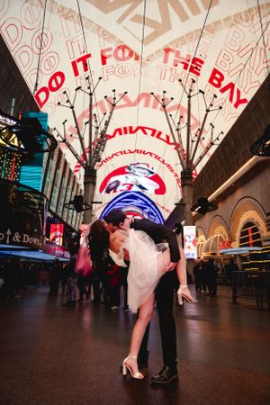 An elopement couple share an intimate moment under the bright neon lights of Fremont Street in Las Vegas.