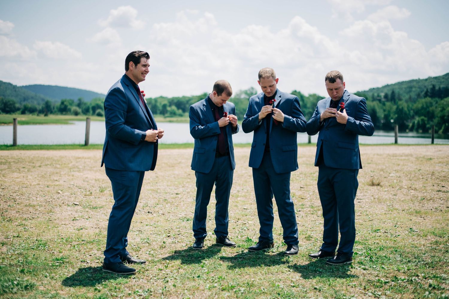groom and groomsmen putting on their boutonnieres