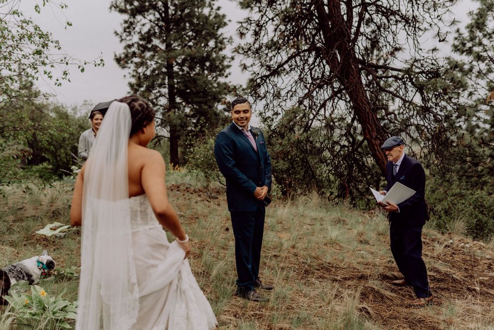 Wedding ceremony in progress on a natural hillside setting among pine trees.