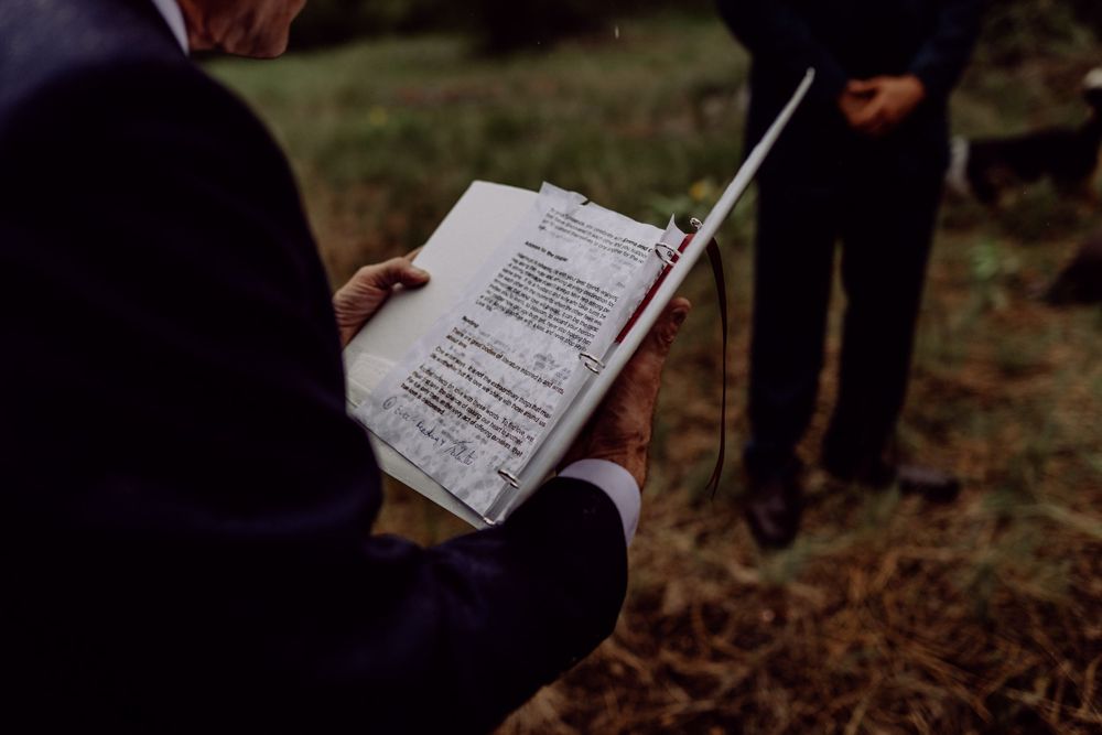 Close-up shot of wedding ceremony paperwork being held during an outdoor service.