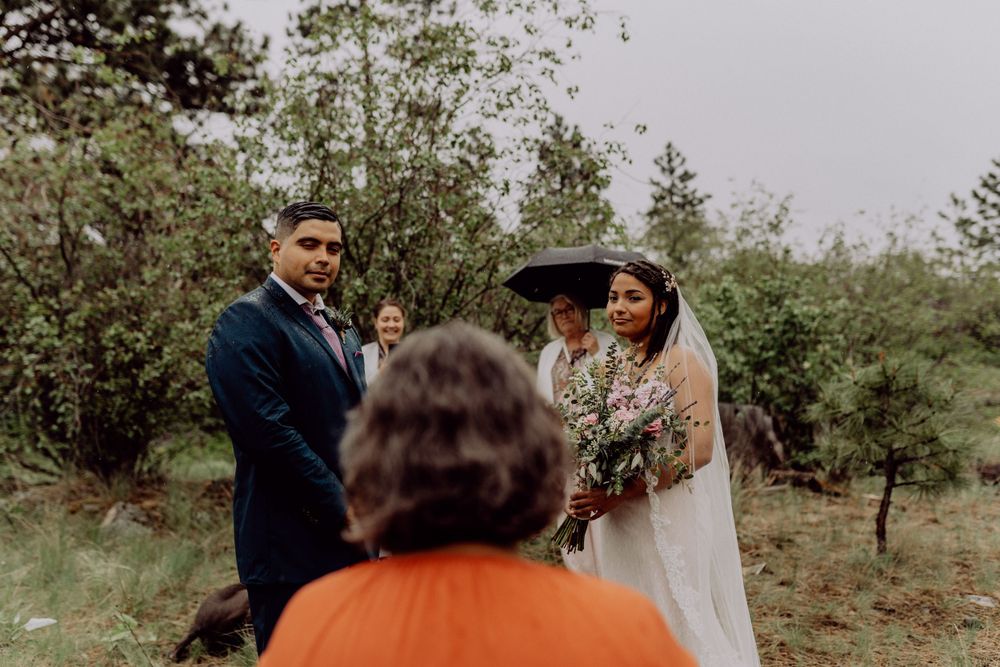 Intimate wedding ceremony taking place on a mountainside with pine trees in the background.