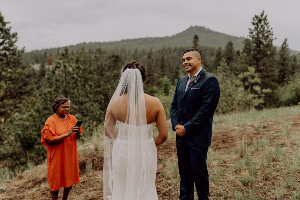 Mountain wedding ceremony with pine forest backdrop and dramatic overcast sky.
