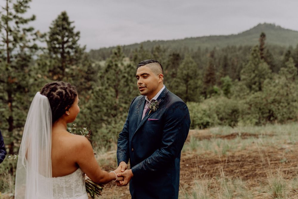 Wedding couple exchanging vows in scenic mountain forest setting.