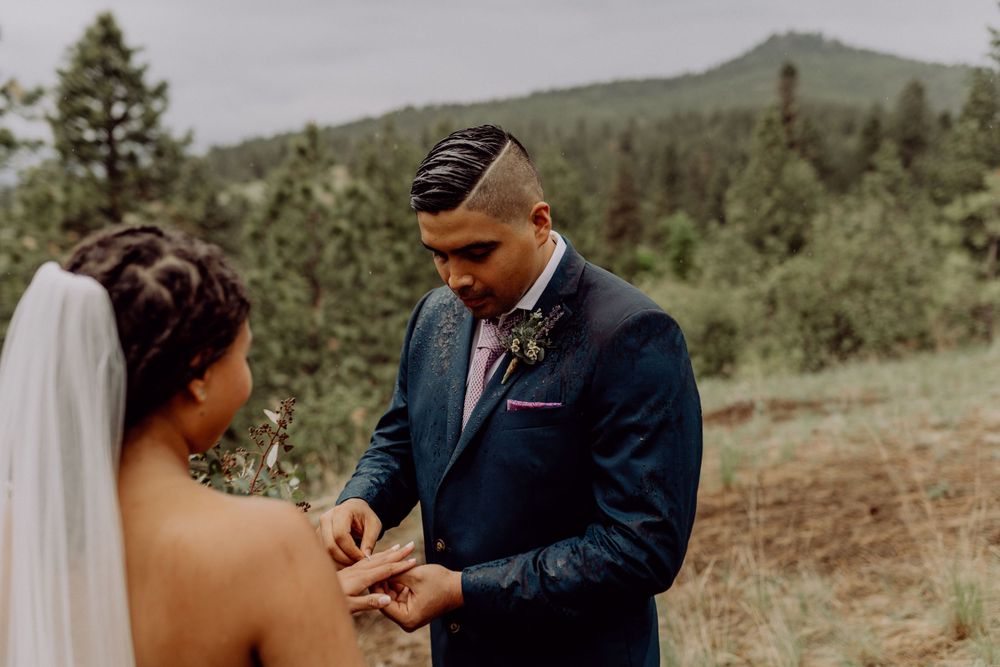A couple exchanges rings during their outdoor mountain wedding ceremony.