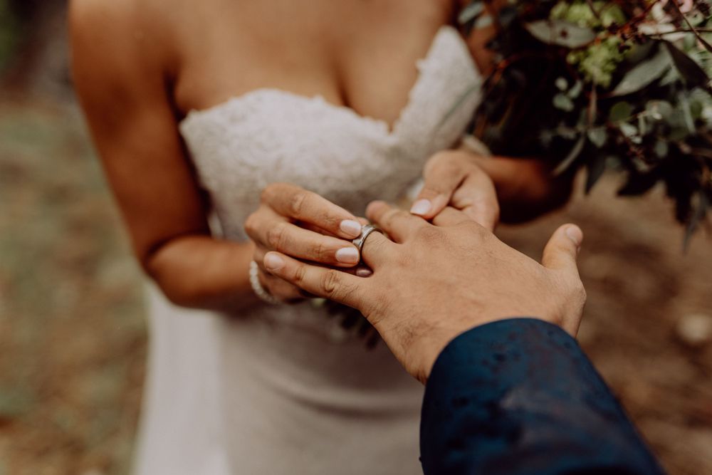 Intimate close-up of wedding rings and hands during an outdoor ceremony.