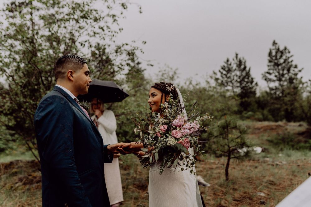 An outdoor wedding ceremony taking place against a backdrop of pine trees and mountains.
