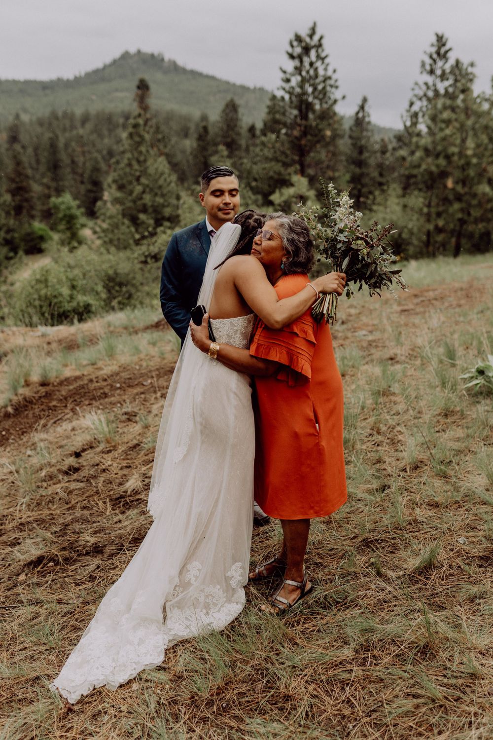 A heartfelt moment shared between wedding attendees on a mountain slope.