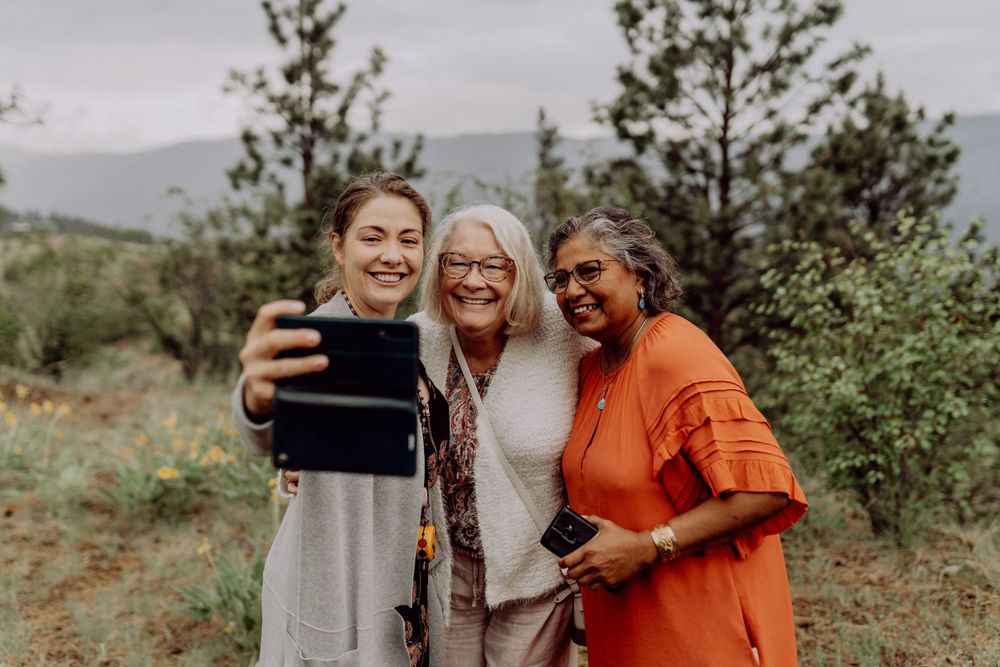 Three friends taking a selfie together outdoors in a mountainous natural setting.