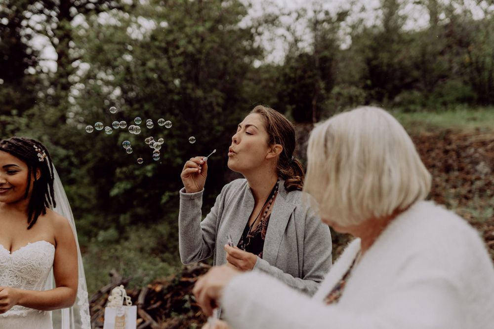 Wedding guests blowing bubbles during an outdoor celebration.
