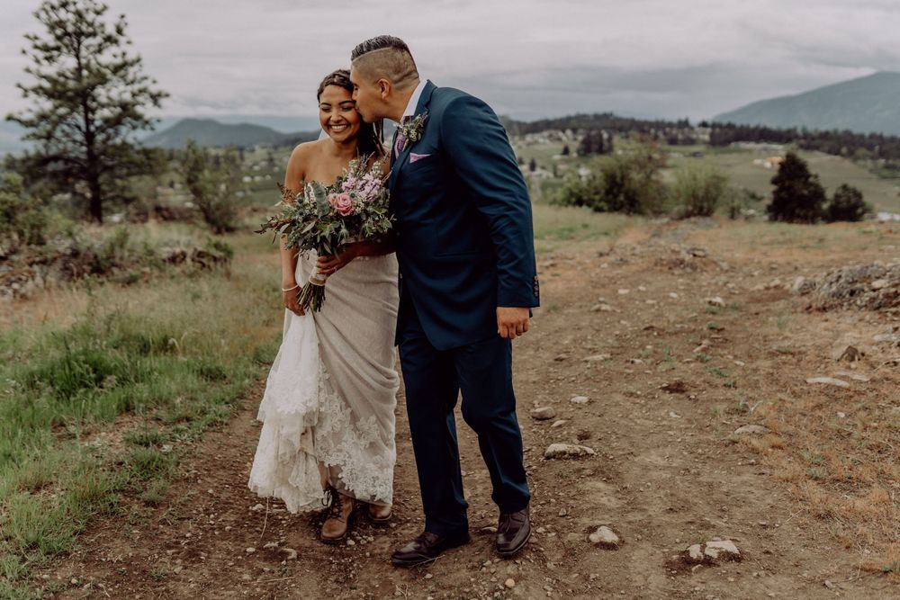 Intimate moment between newlyweds on a scenic mountain path.