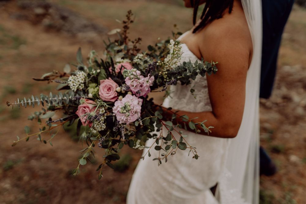 Close-up of pink and white wedding bouquet with roses and greenery.