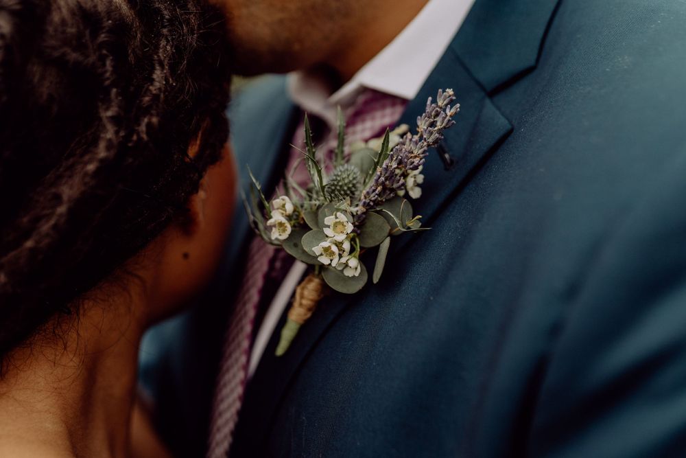 Detailed shot of boutonniere with delicate flowers pinned to navy suit jacket.