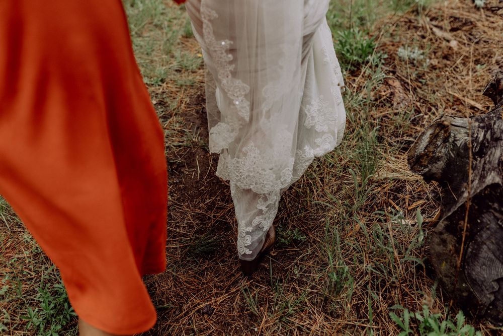 Flowing white wedding dress and orange attire captured from ground level.