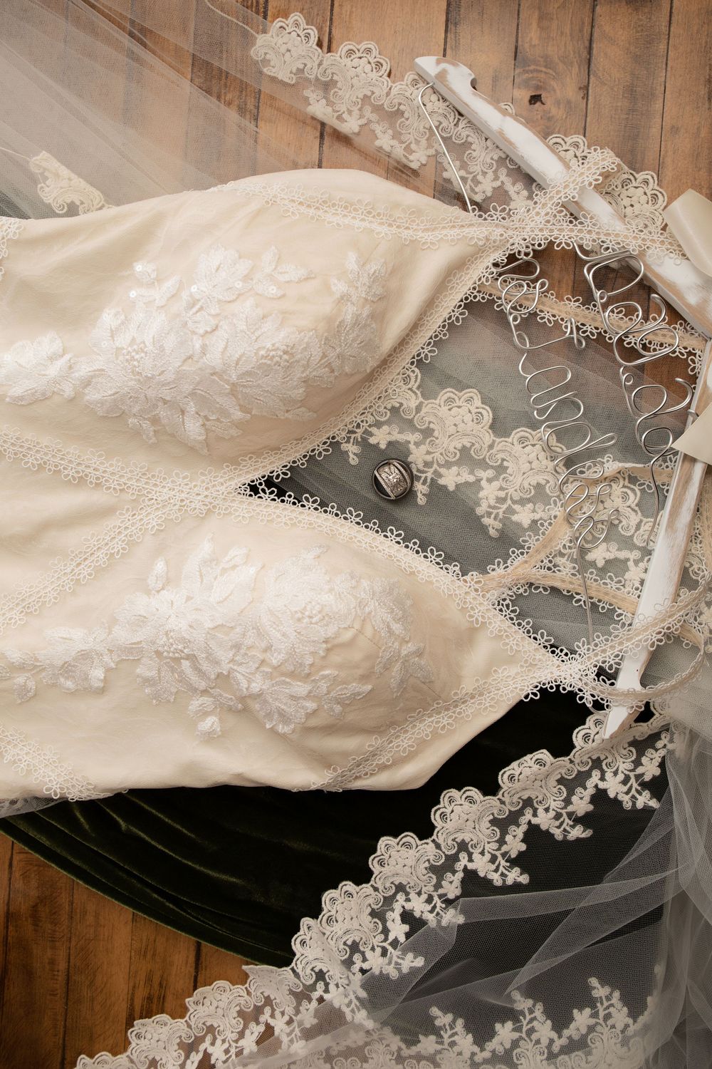 Elegant white lace wedding dress bodice with intricate beading on wooden floor.