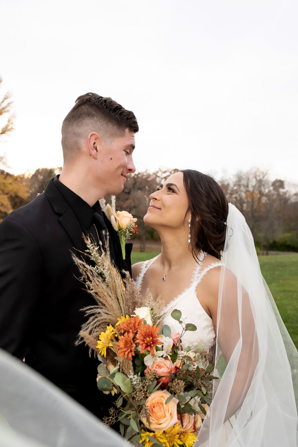 Romantic wedding couple moment with fall bouquet featuring orange roses and pampas grass.