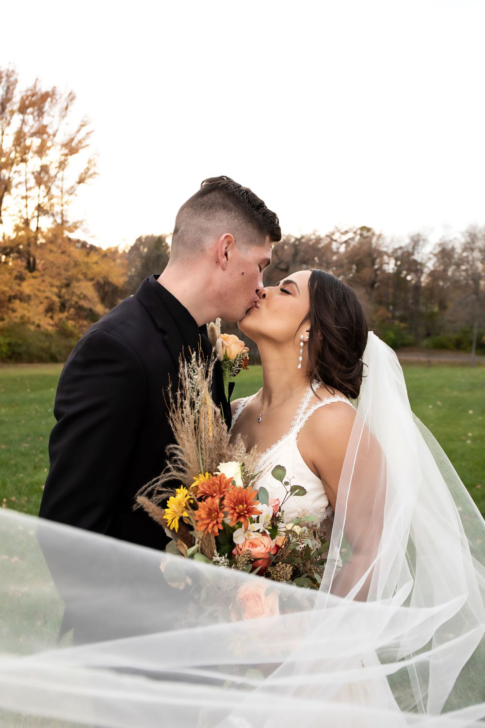 Intimate wedding portrait with flowing veil and autumn florals.