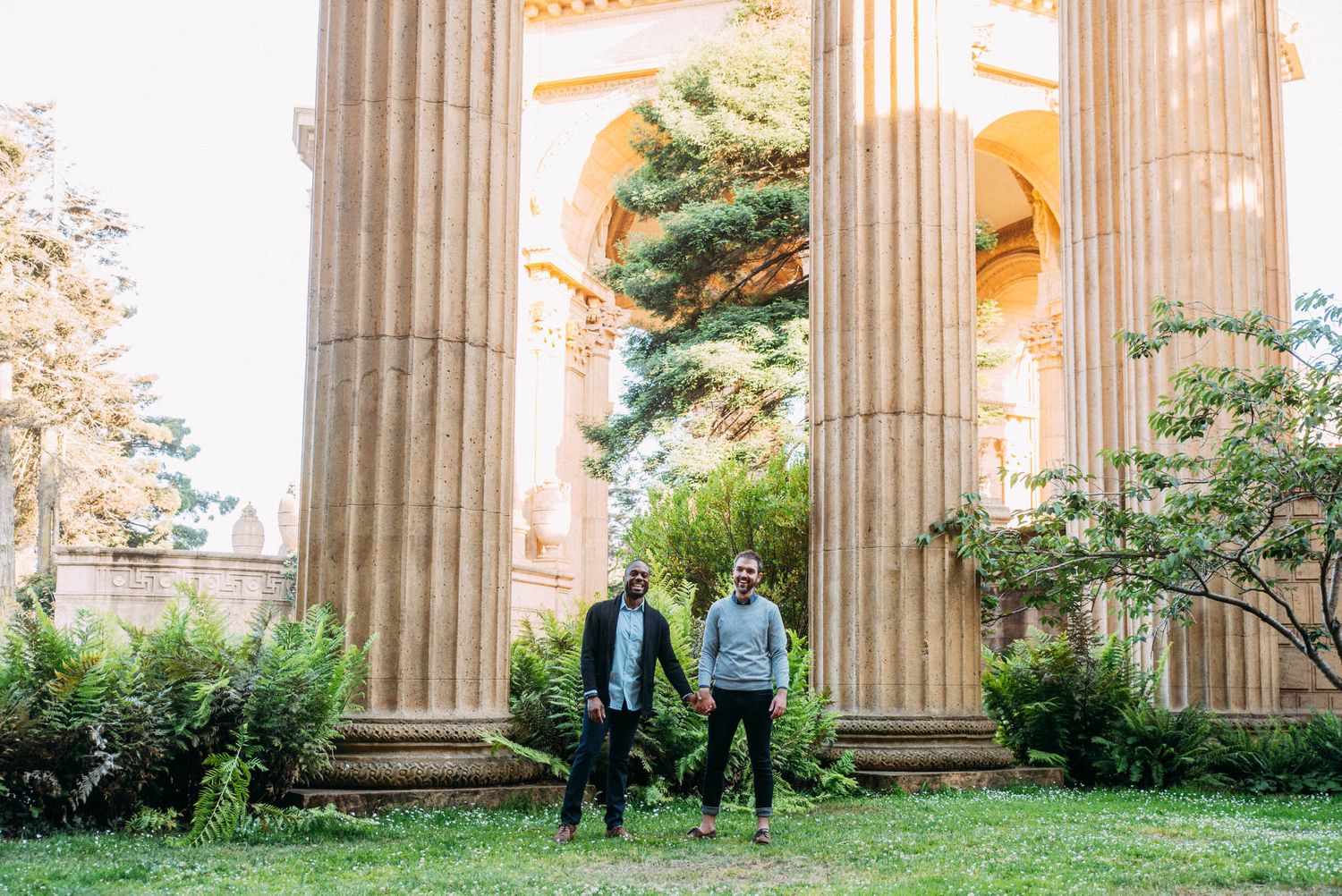LGBTQ+ male couple hold hands at Palace of Fine Arts in San Francisco for engagement portraits.