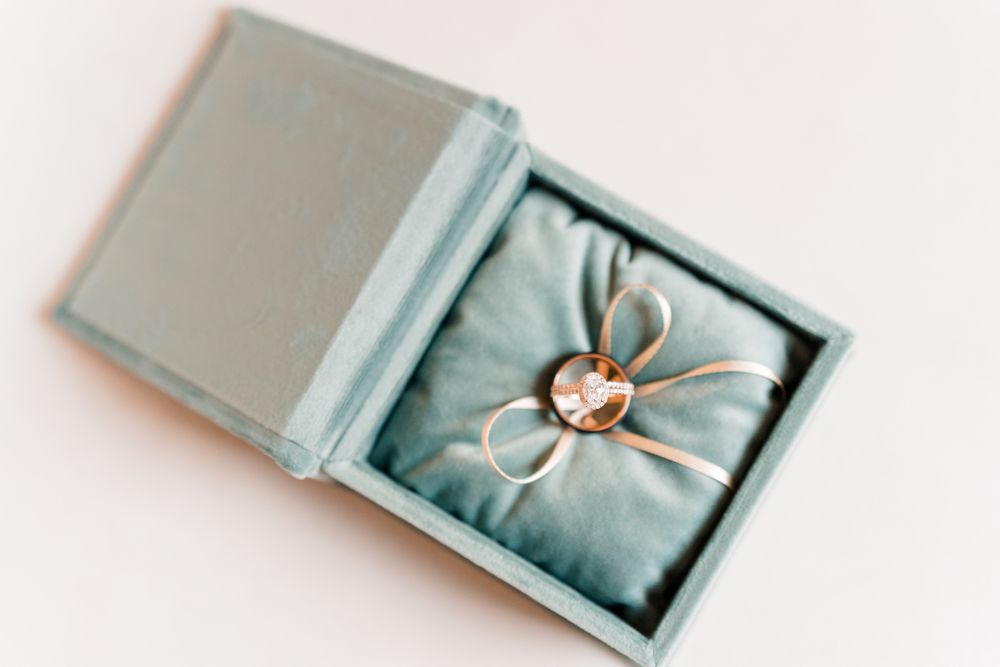 A delicate silver ring displayed in a light blue jewelry box with silk lining.