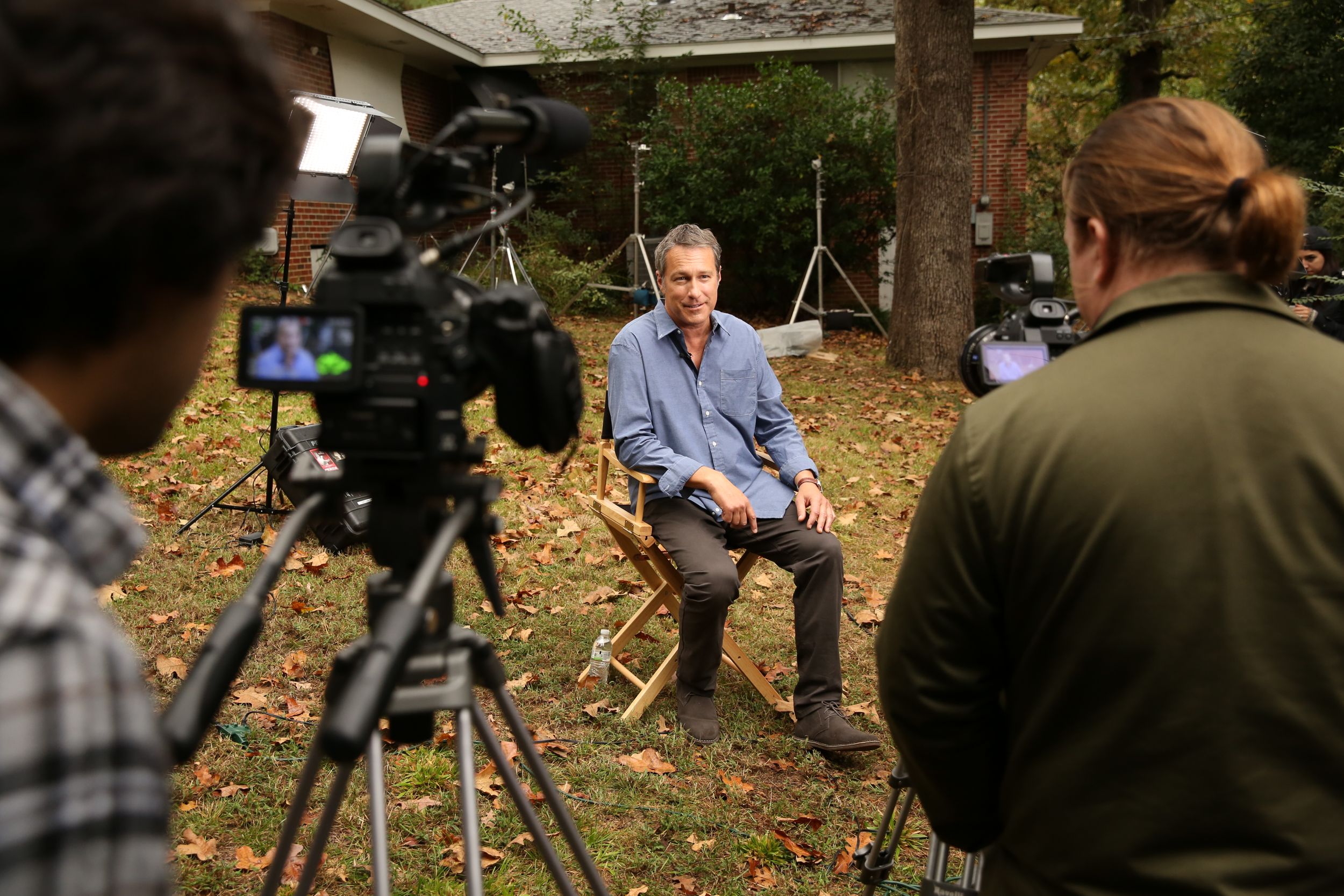 Film production crew working with camera equipment outdoors in a leafy setting.