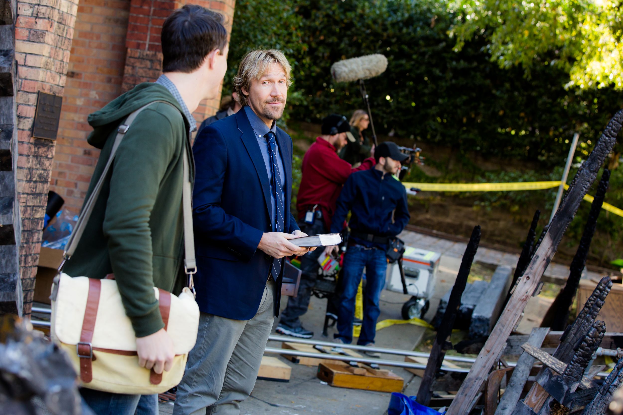 Production crew members discussing scene details between takes on an outdoor film set.