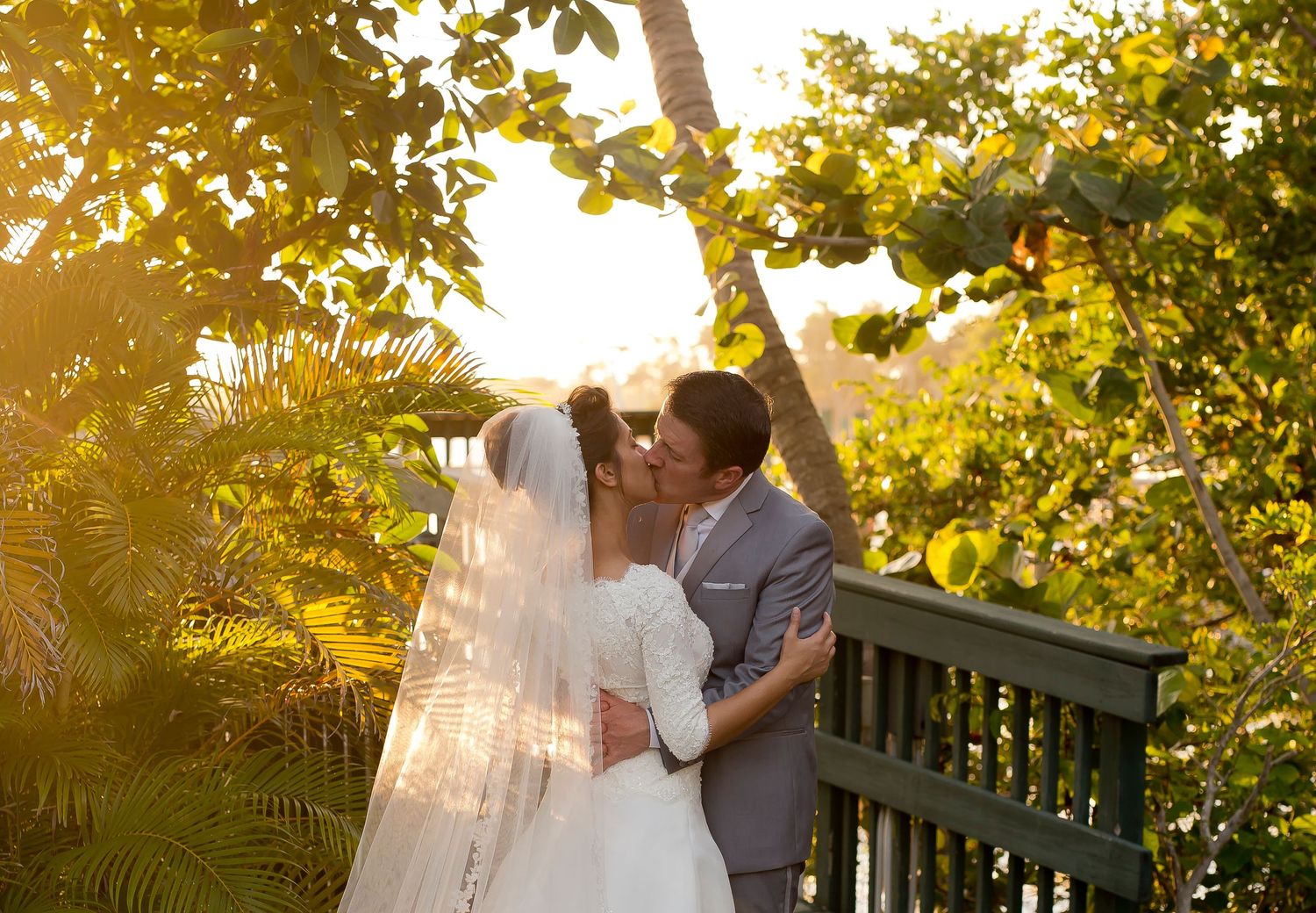 Wedding party posing on wooden deck surrounded by lush summer foliage.