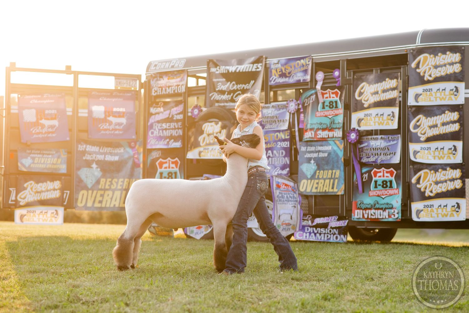 Show lamb being presented in front of banner-covered display wall at outdoor competition.