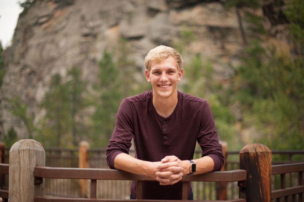 Senior portraits taken against rocky mountain backdrop.