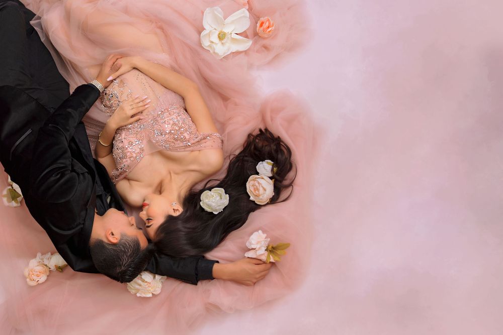 Ethereal overhead maternity photo with scattered white and pink flowers.