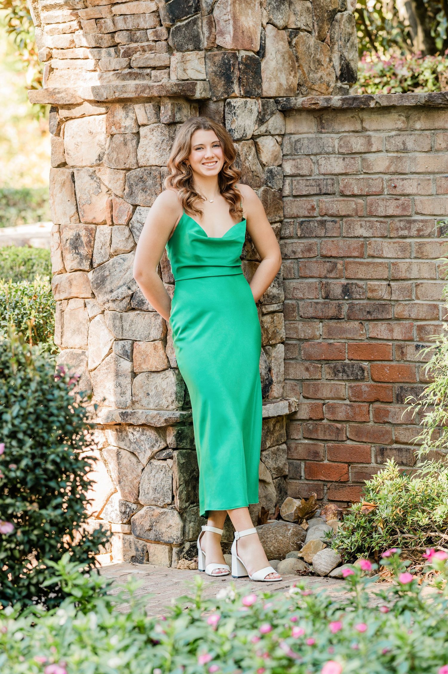 Portrait session by rustic brick and stone wall featuring bright green summer dress.