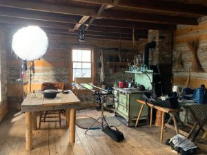 Rustic workshop film set with wooden furniture, lighting equipment and vintage green stove.