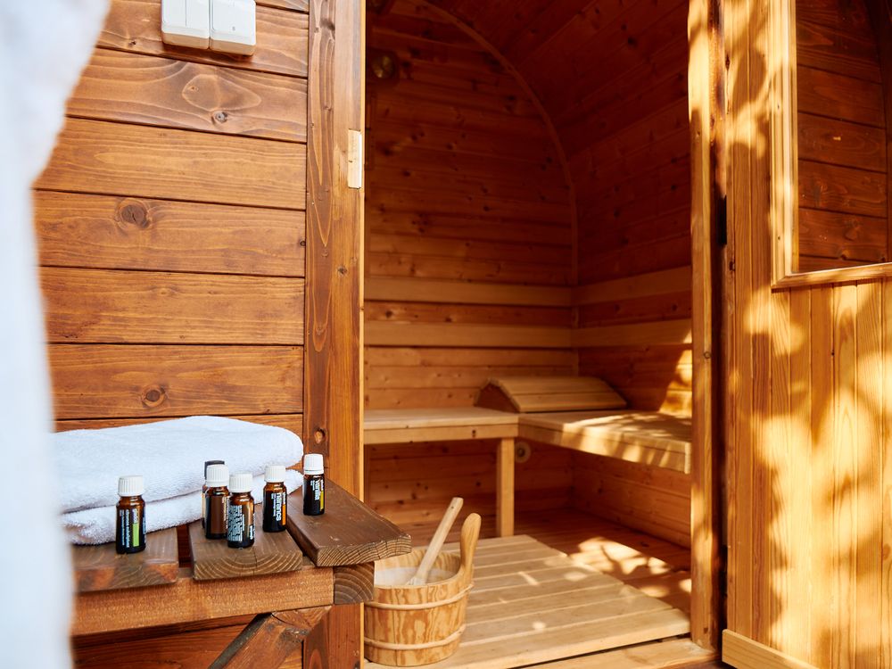 Interior of a wooden sauna with benches and traditional sauna accessories on a side table.