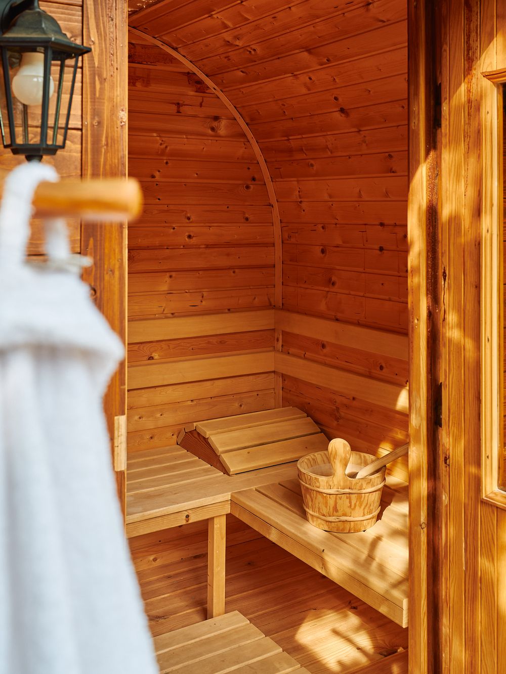Interior view of wooden sauna with bench seating and traditional water bucket.