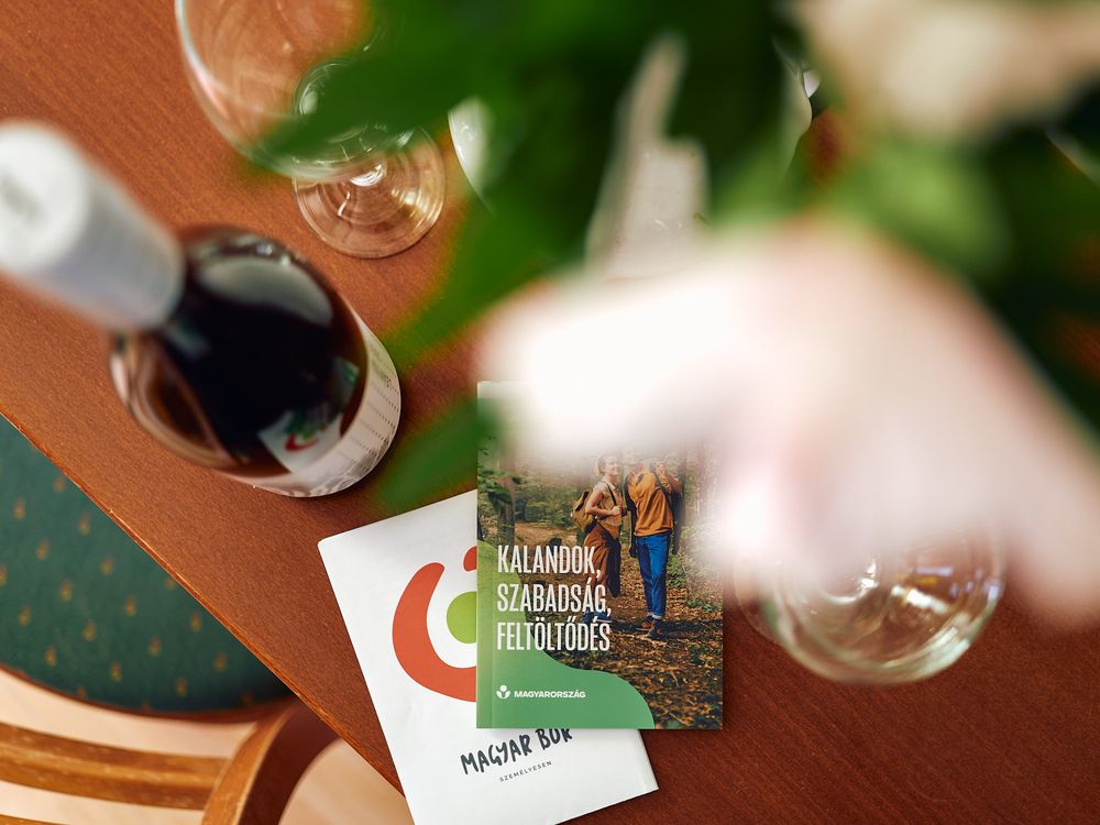 Wine bottle and glasses on wooden table with business cards and greenery.