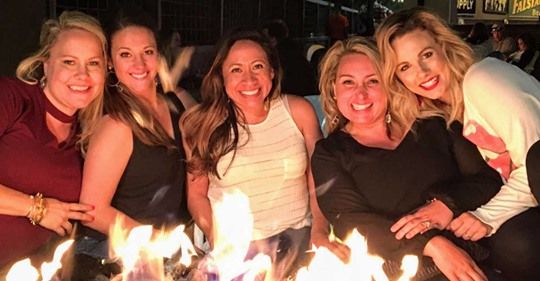 Friends gather around glowing candles in a dimly lit setting.