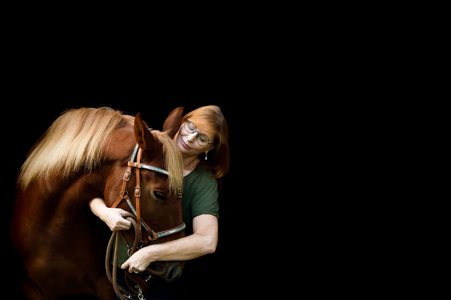 Woman with red hair, eyes closed,  hugging Chestnut horse's face
