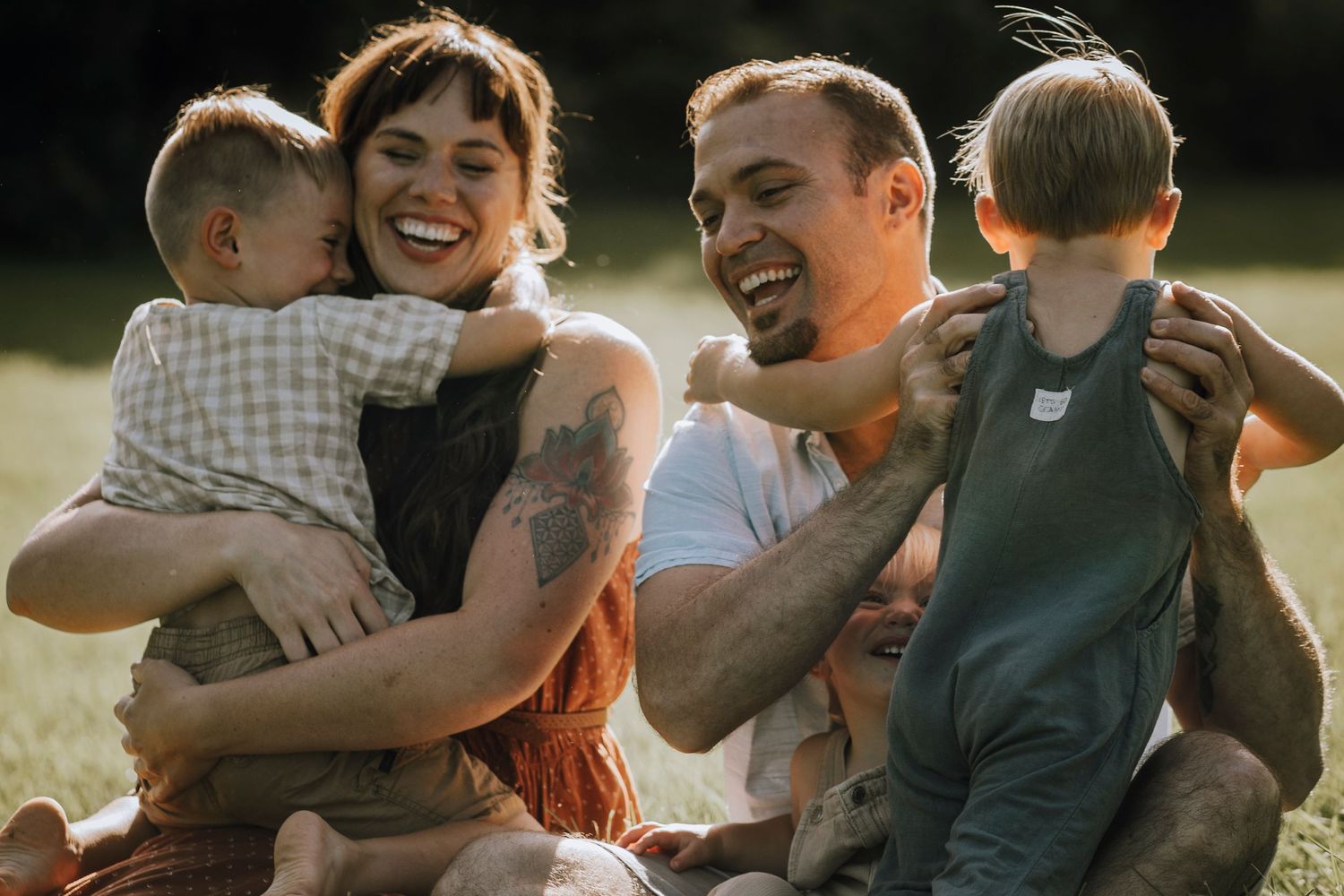 Family enjoying a sunny day outdoors while sitting together on grass.
