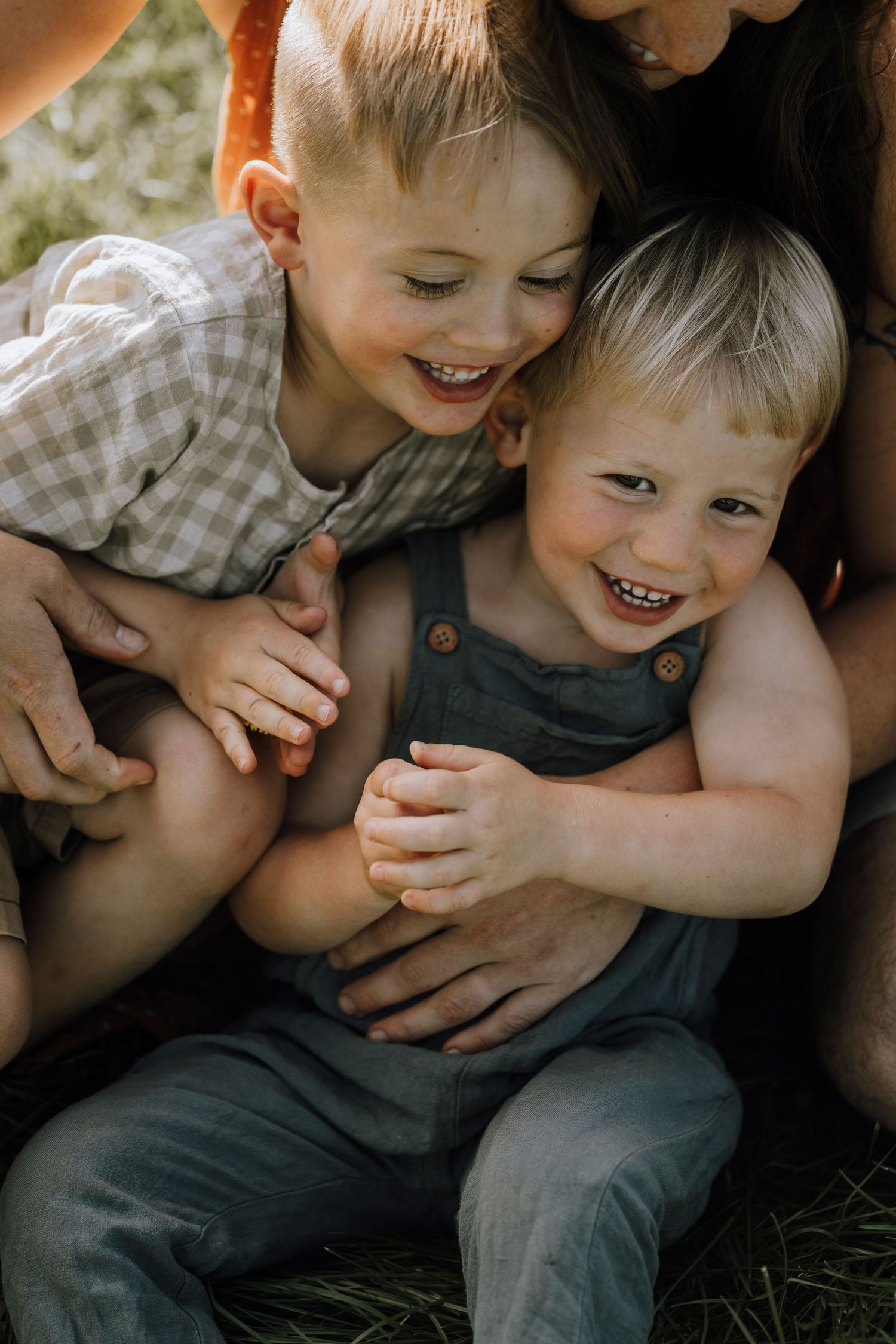 Two children laughing and embracing while sitting outdoors.