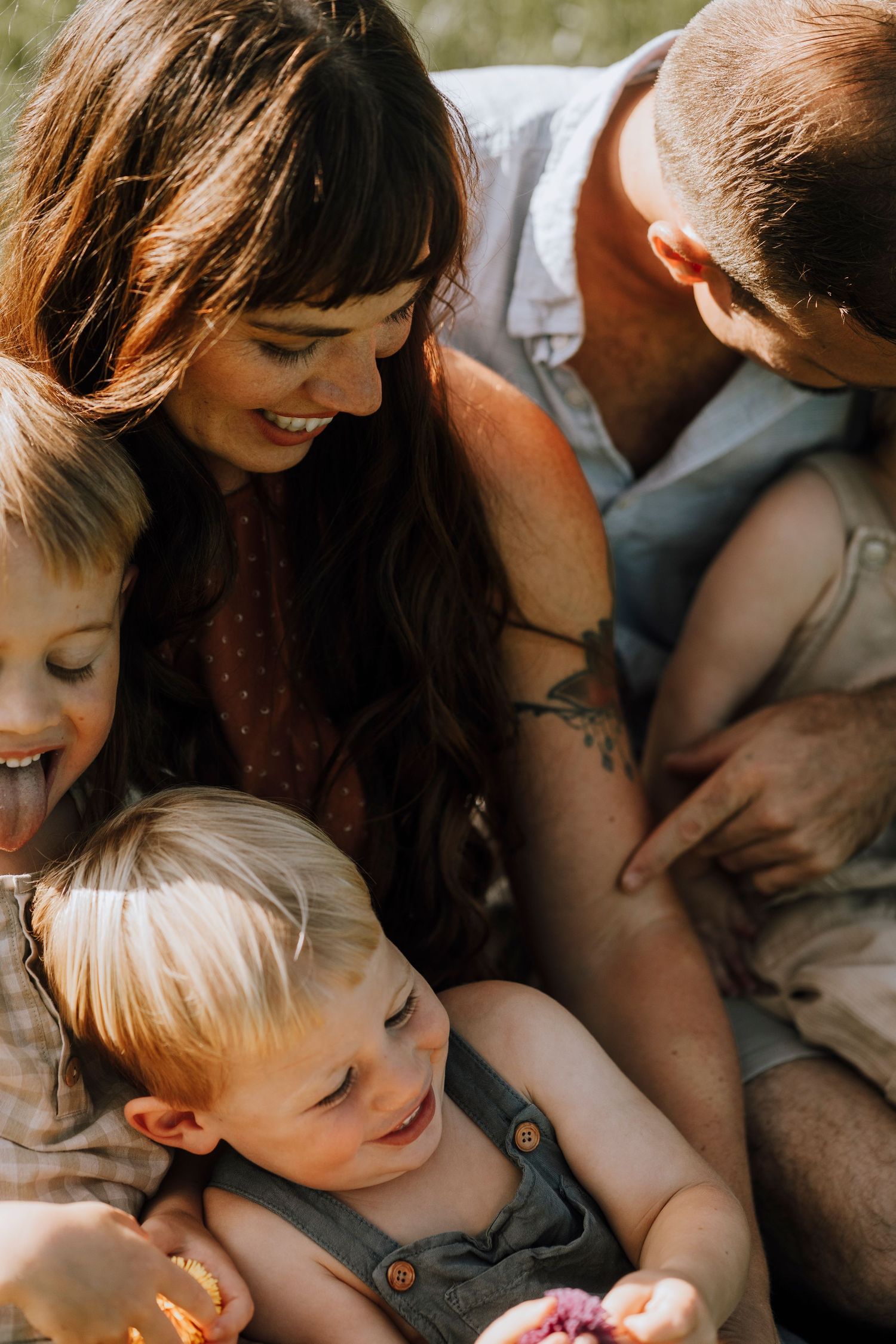 Family sharing intimate moment together while sitting in sunlit field.