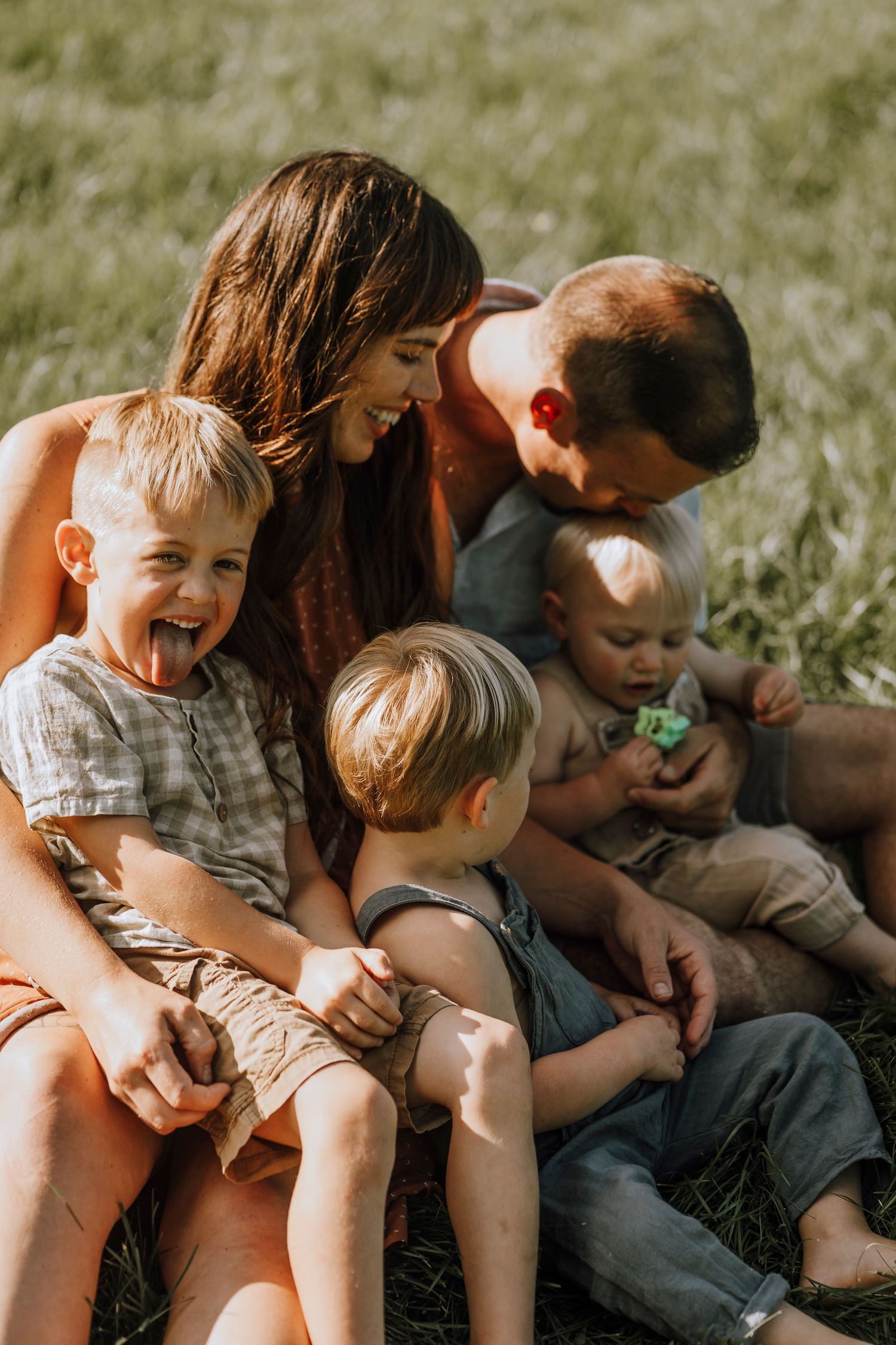 Family sharing playful moment together on sunny grass field.