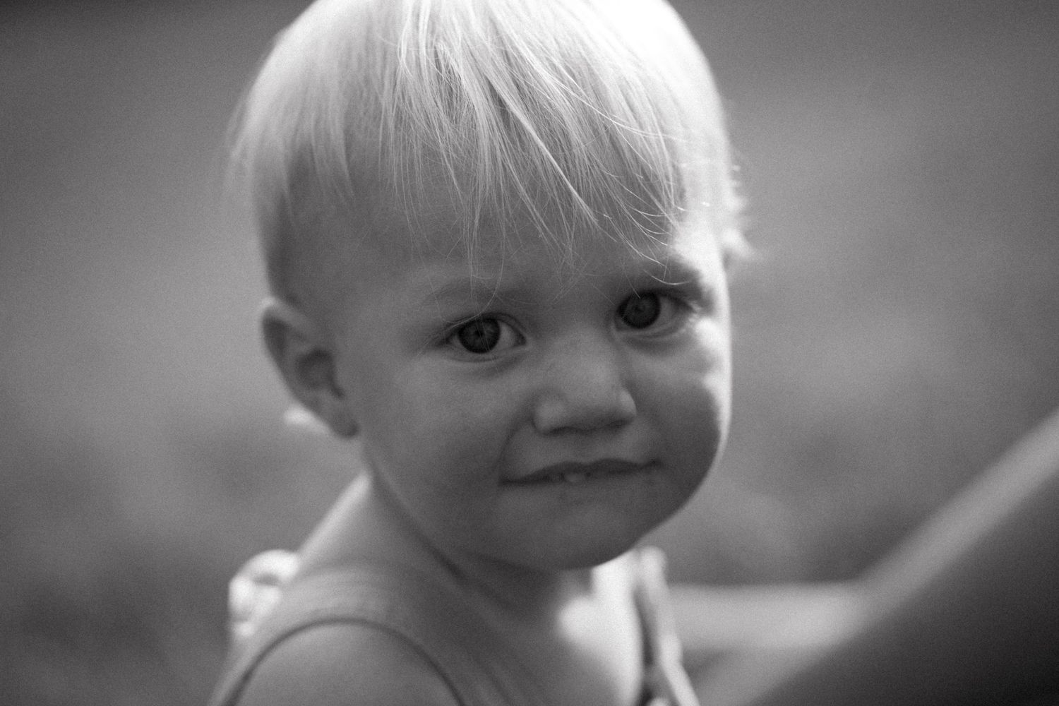 Black and white portrait of toddler with gentle smile.