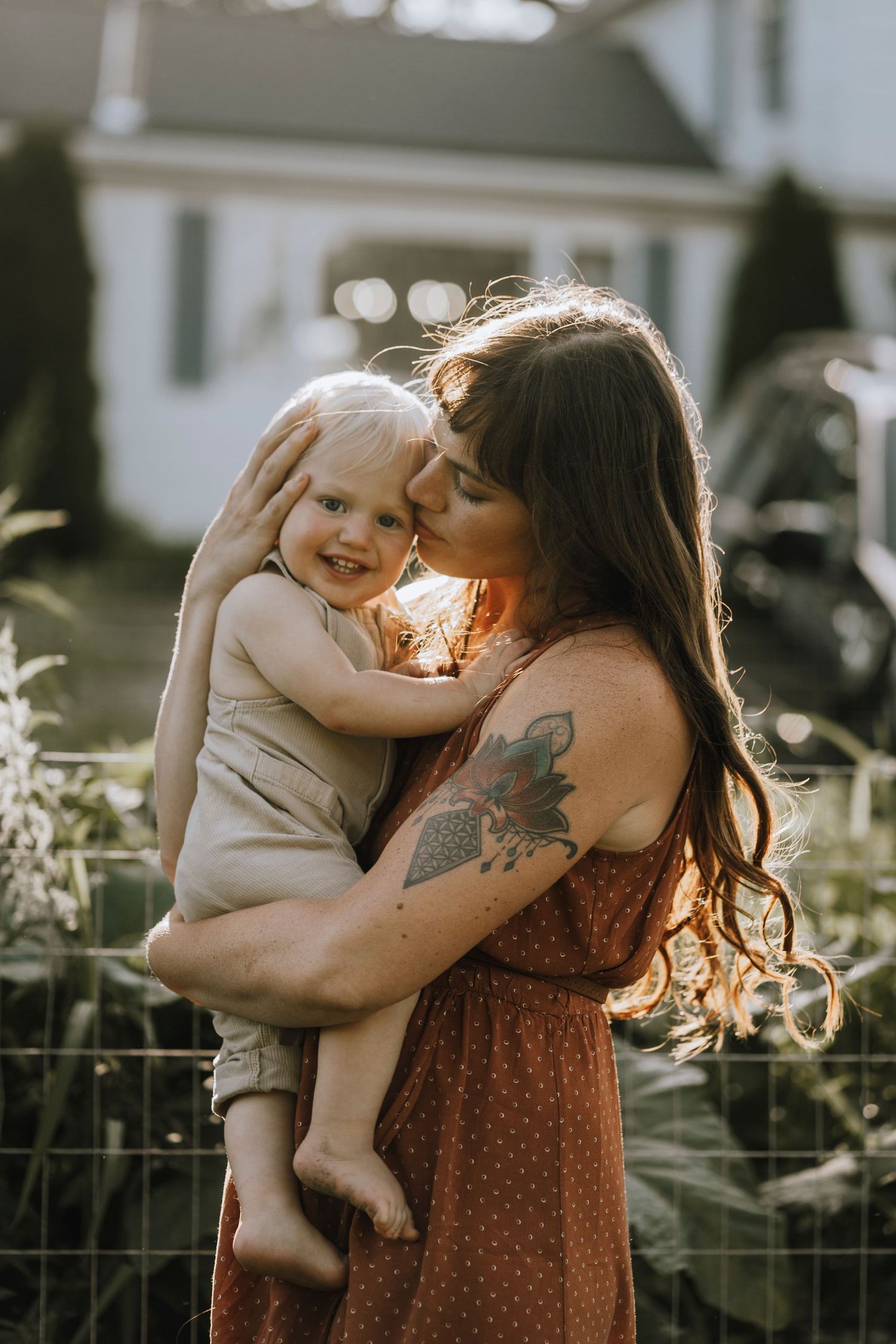 A tender embrace shared between parent and child in sun-dappled garden setting.