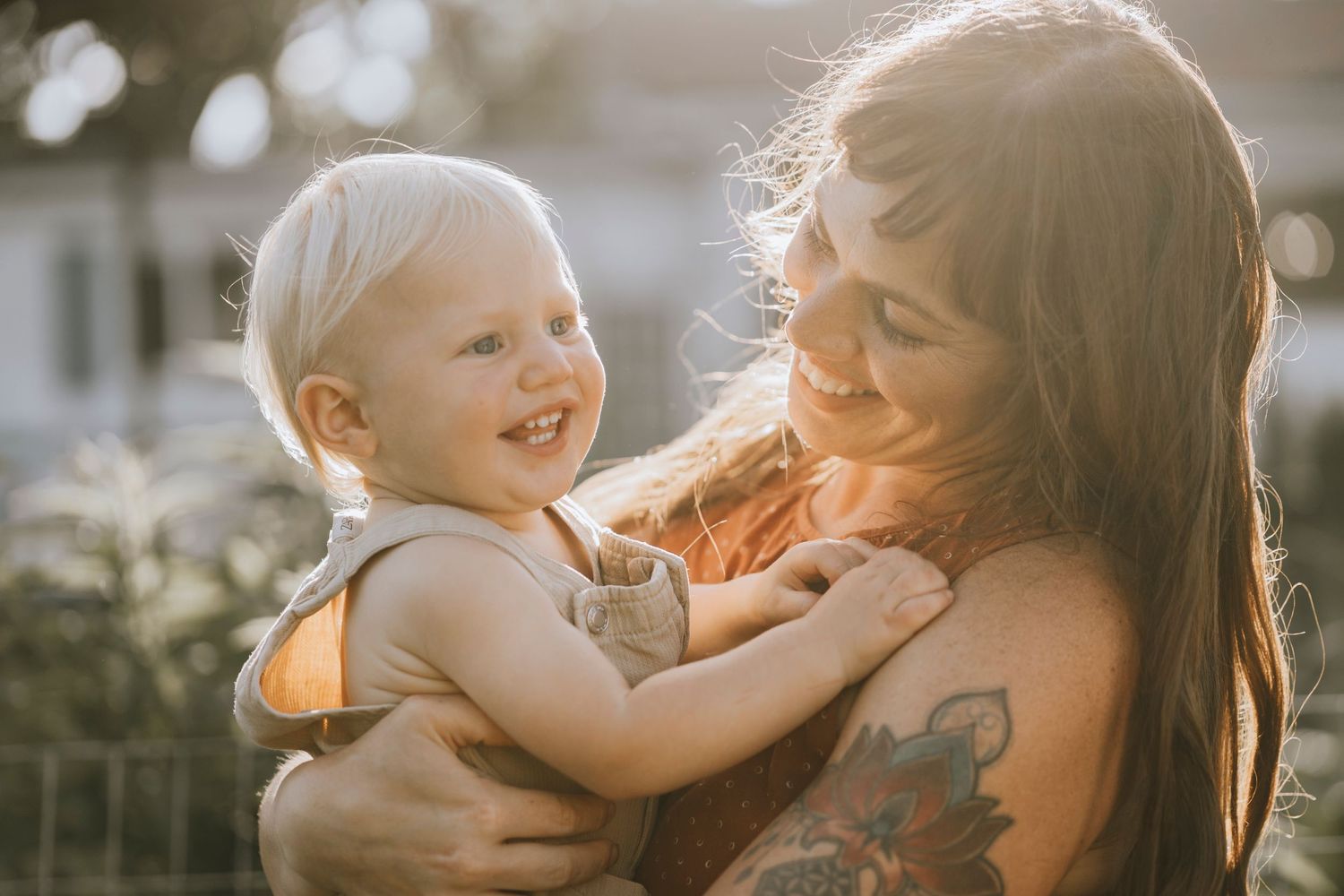 Joyful moment shared between parent and laughing child in backyard setting.