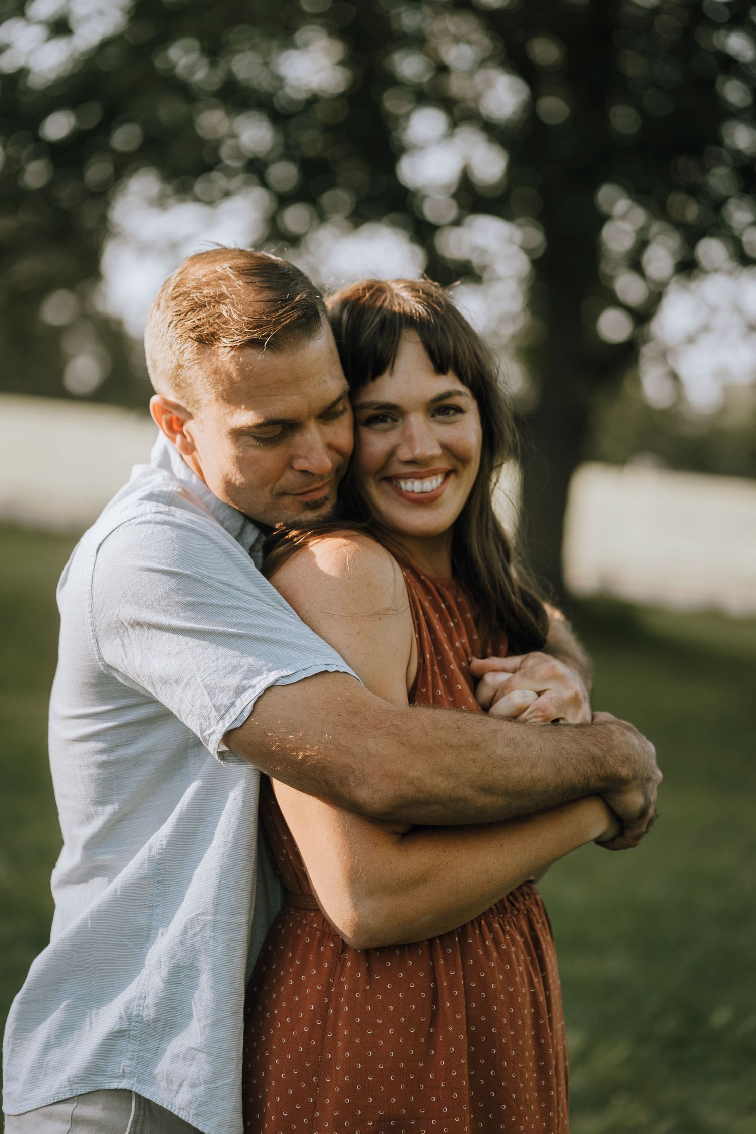 Intimate embrace shared between couple in casual attire outdoors.
