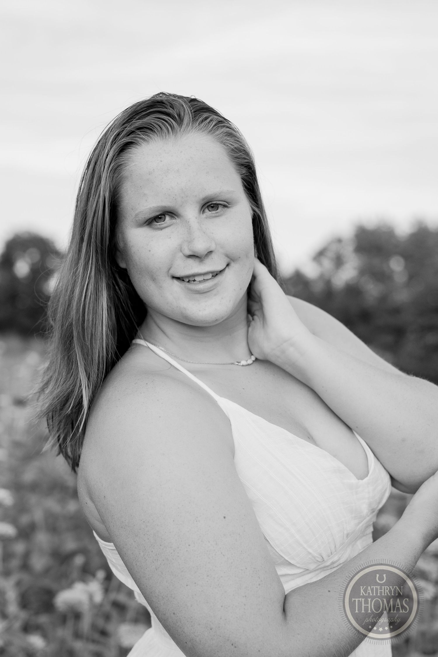 Black and white portrait of someone in white dress posing in outdoor setting.